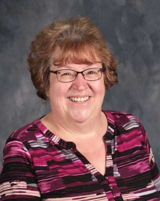 headshot of a woman with specs smiling